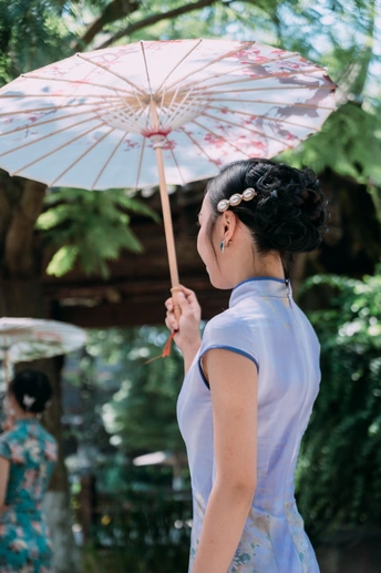 一位年轻女士穿着一件裙子 手里拿着一把白色雨伞。