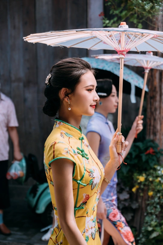 一位穿着黄色连衣裙的年轻女子手持雨伞