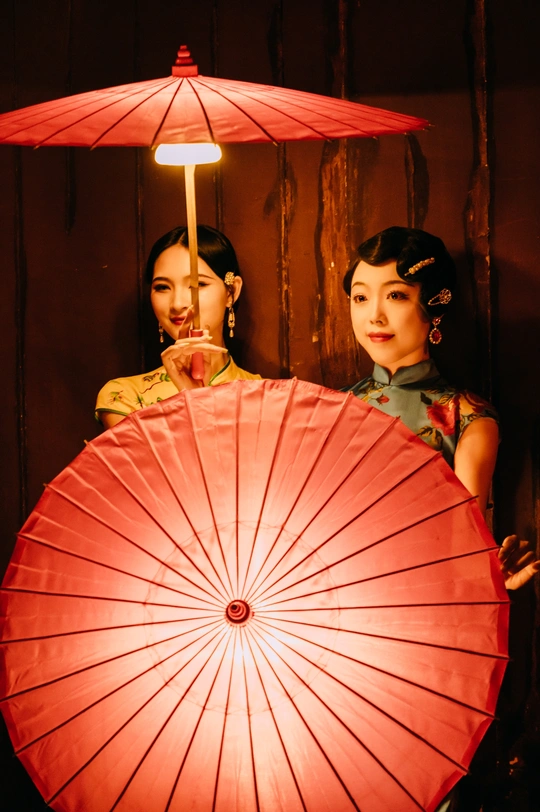 一位女性拿着红伞站在另一位女性旁边