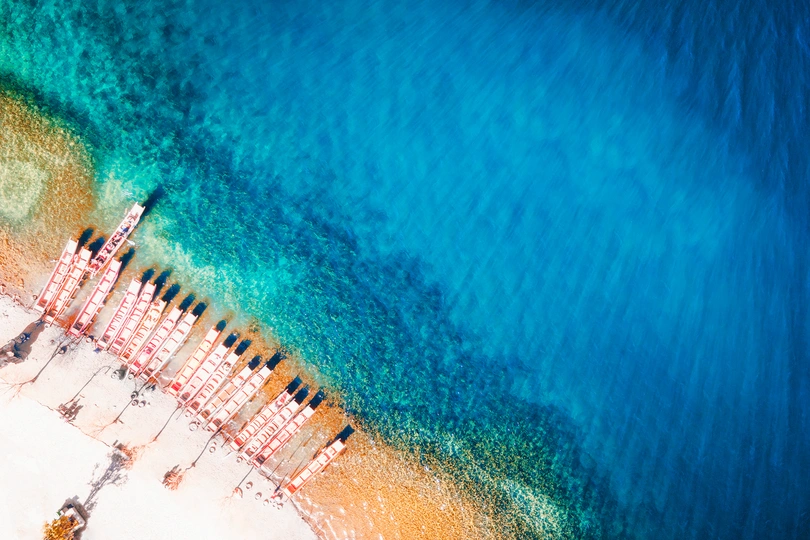 带有遮阳伞、椅子和蓝色水的海滩的 aerial view