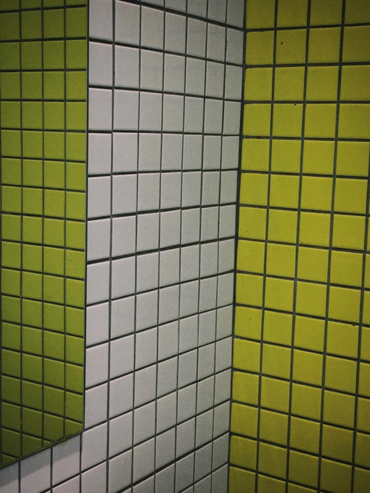 一个带有绿色和黄色瓷砖的浴室里的一个小便池