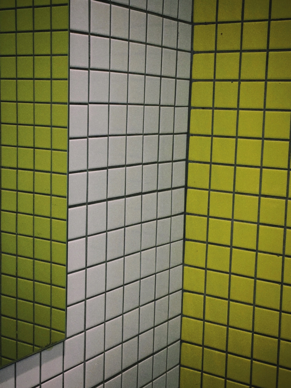 一个带有绿色和黄色瓷砖的浴室里的一个小便池