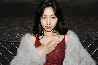 一位穿着红色连衣裙和皮草大衣的女士坐在长凳上
