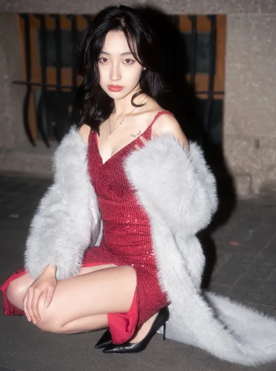 一位穿着红色连衣裙和白色皮草大衣的女人