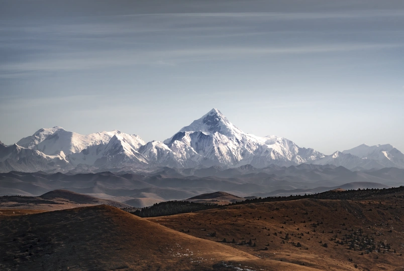 前景有山丘的雪景山脉