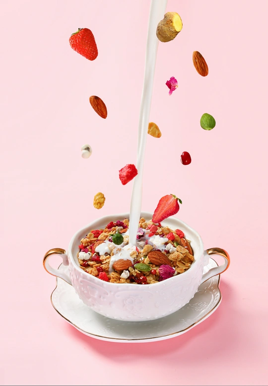 一杯麦片 里面倒入牛奶 草莓和坚果从碗里掉了出来