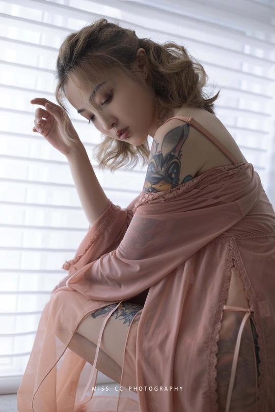 一个穿着粉色连衣裙的小女孩坐在椅子上看着窗外