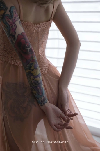 一个穿着粉红色连衣裙、手臂上有纹身的女孩