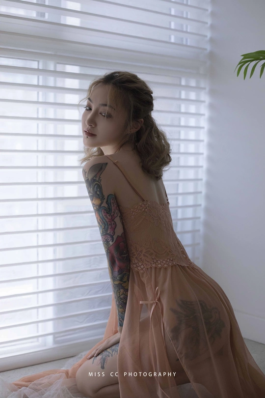 一个纹身的年轻漂亮女人在窗前摆姿势