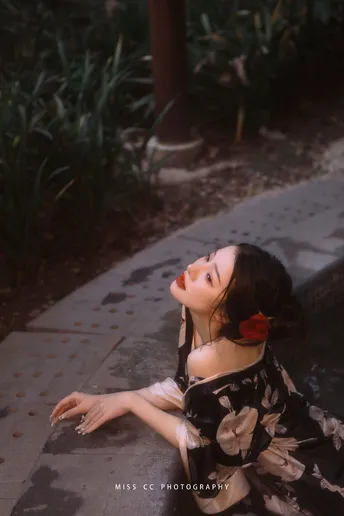 一个穿着连衣裙的年轻女子坐在人行道上 带着一把雨伞。