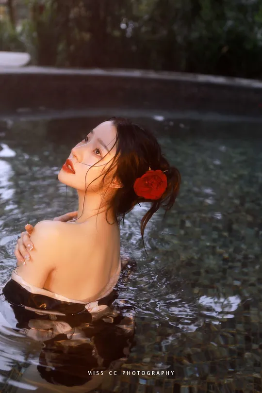 一位年轻女子头戴红花 在水坑中。