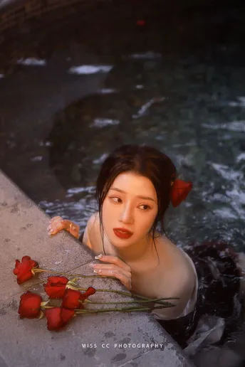 一位女子躺在带有红玫瑰的泳池中