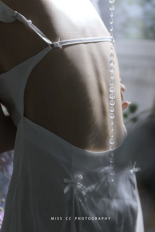 一位怀孕的妇女穿着一件白色的连衣裙站在窗户前