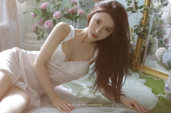 一个穿着白色连衣裙的年轻女子躺在床上 床边有一幅画。