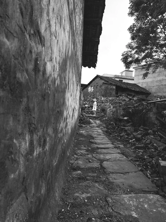 一位女孩走在老建筑之间的巷子里