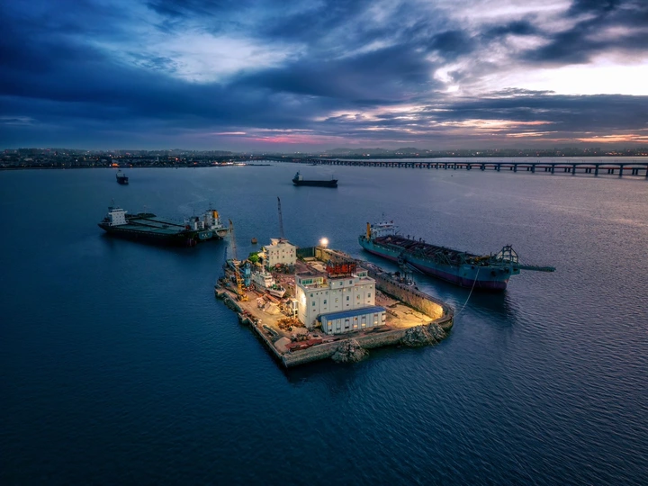 夕阳下港口的空中视角 大型船舶和驳船在水中。