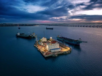 夕阳下港口的空中视角 大型船舶和驳船在水中。