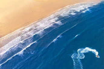 冲浪者在蓝色海洋中骑浪的 aerial view