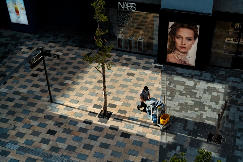 一个男人走在街上 旁边是一棵树和一个女人