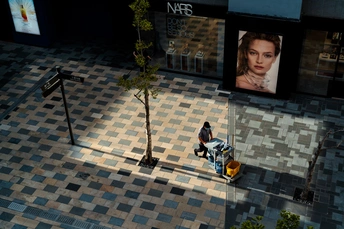 一个男人走在街上 旁边是一棵树和一个女人