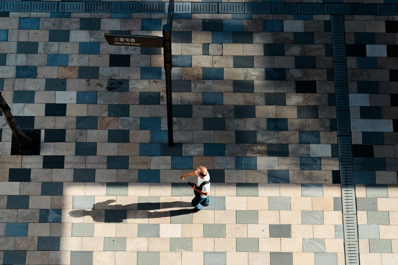 一男一女走在人行道上 地上有他们的影子 背景是一栋建筑