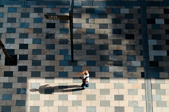 一男一女走在人行道上 地上有他们的影子 背景是一栋建筑