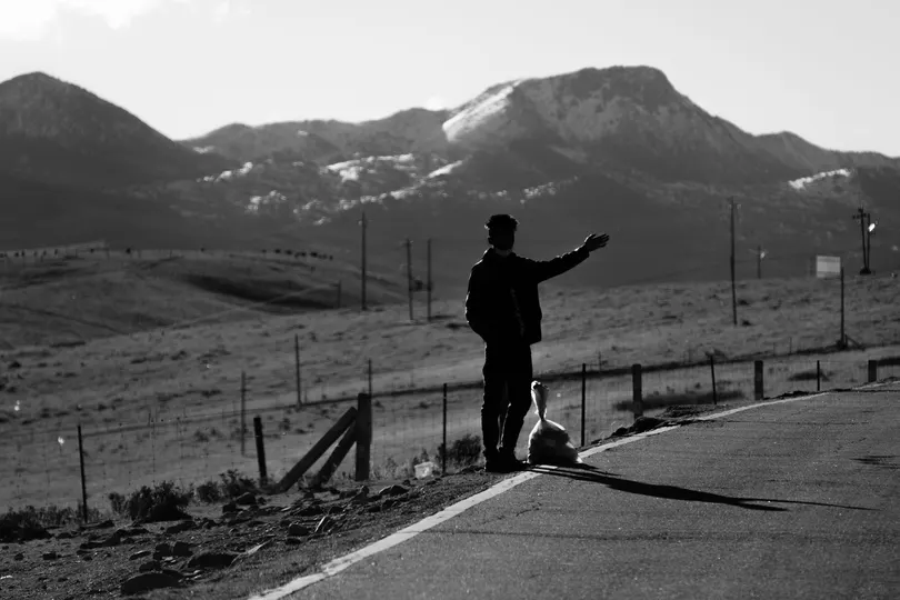 站在路边 背景是山脉的一个男人