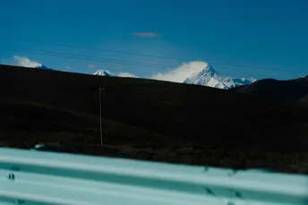 一辆蓝色的汽车窗户 可以看到一片白雪皑皑的山脉和山丘。