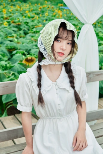一个穿着白色连衣裙、戴着帽子的年轻女孩坐在长椅上