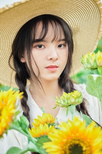 一位戴着草帽的年轻女子在一片黄色的花田里捧着向日葵的画像