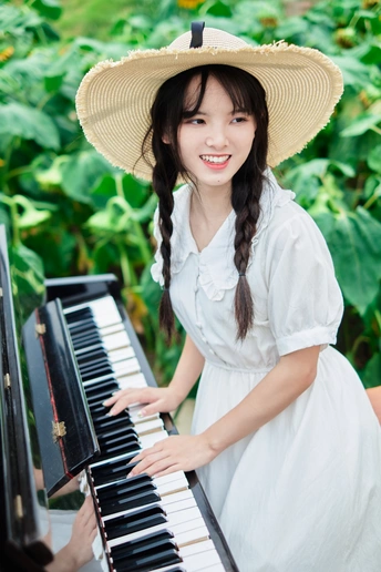 一个穿着白色连衣裙、戴着草帽的年轻女子在外面弹钢琴