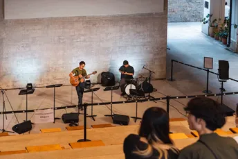 一个建筑物内的房间 一个人在弹奏乐器 一群人坐着