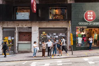 行人站在城市一家商店和餐厅的人行道上