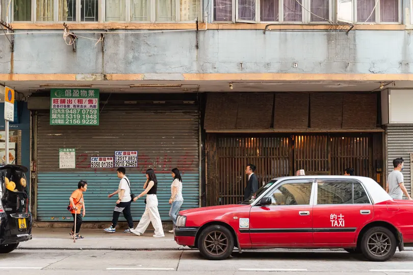 一辆红色的车停在建筑物前面 人们沿着街道走下来。