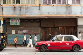 一辆红色的车停在建筑物前面 人们沿着街道走下来。