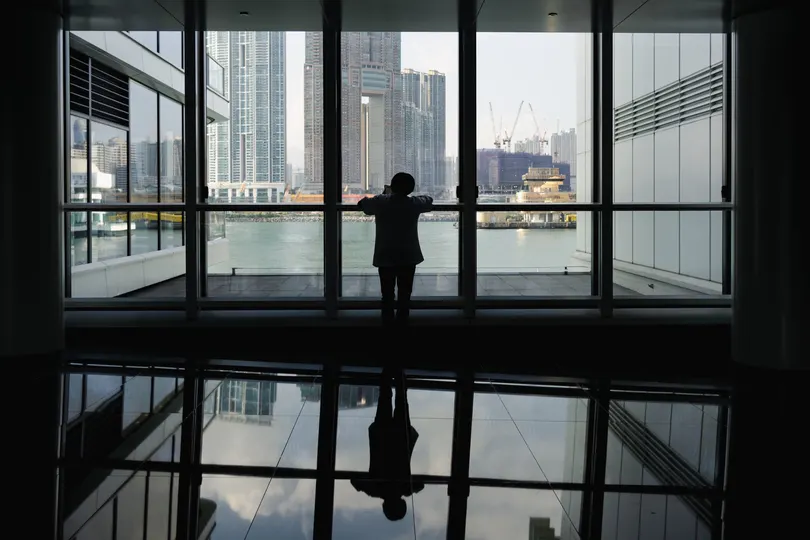 一位站在大型窗户前 凝视着水面上的城市倒影的女人剪影