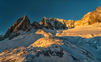 雪覆盖的山脉在日出或日落时被阳光照亮