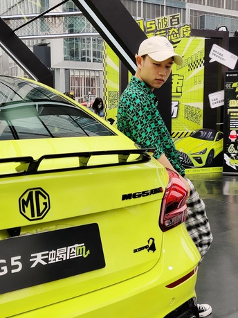 在一场演出中 一个男人站在一辆黄色汽车旁边