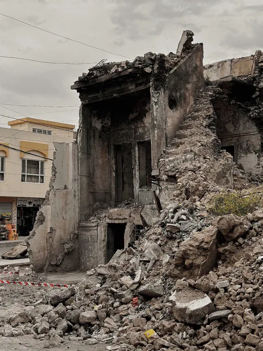 一片被毁的城镇中的一条街道 前方有被毁房屋的瓦砾和碎片。