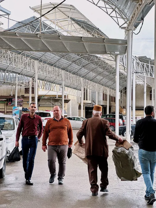 许多人提着行李走过一个火车站。