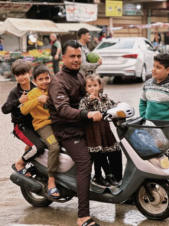 一个人骑着摩托车带着小孩子们和一家人在街上。