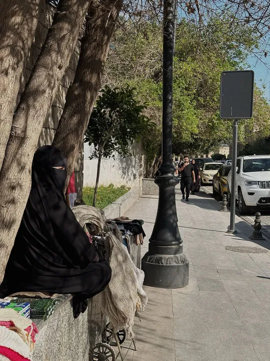 一个人坐在墙上 靠着一棵树 当一个女人走下人行道时