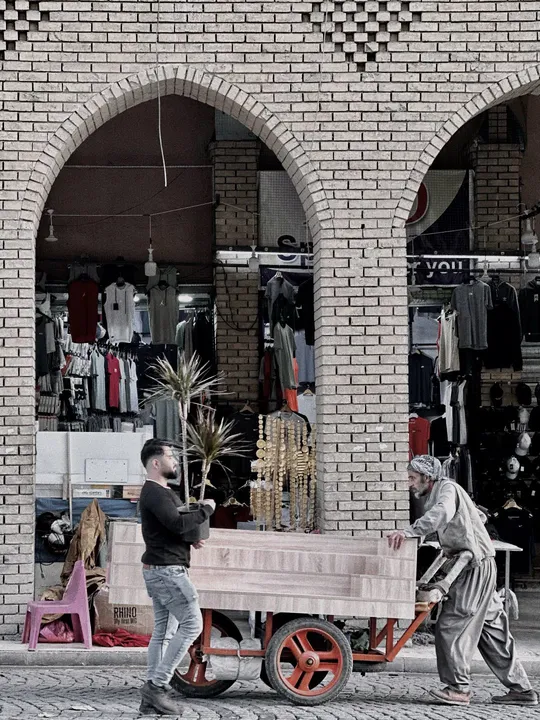 一个人推着木车经过商店前面的街道