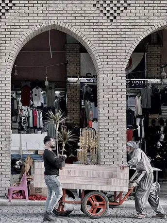 一个人推着木车经过商店前面的街道