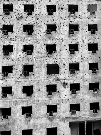 一座古老的建筑 有许多窗户和一堵高大的混凝土墙。