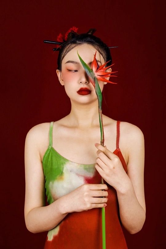 一位穿着绿色连衣裙的年轻女子手里拿着一朵红花