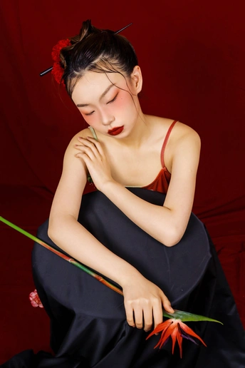 一位穿着黑色连衣裙的年轻女子手里拿着一朵红花