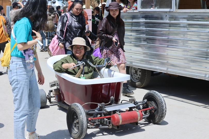 一个小车由一个妇女拖着在街上行驶 还有其他人。