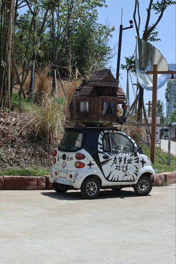 一辆停在路边的小型车辆 车顶上有涂鸦 顶部有树屋。