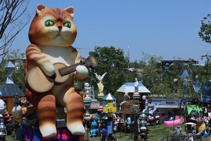 一场有大型猫在花车上 人们在公园里的嘉年华